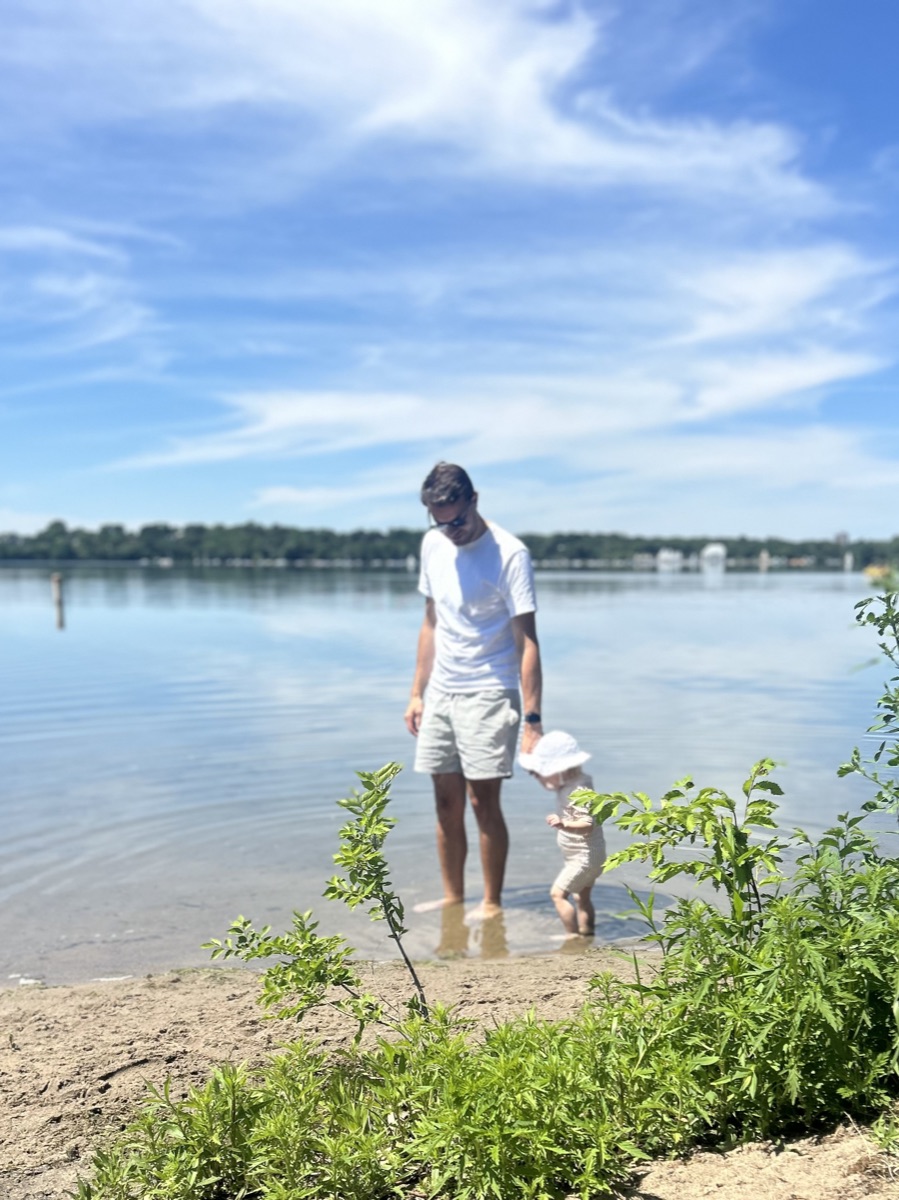 A parent and child paddling at the water's edge.